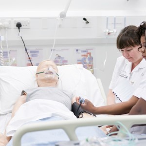 Students studying a dummy in a simulation nursing ward